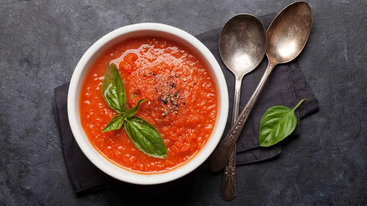 Schüssel mit frischer Tomatensauce, garniert mit Basilikum und Pfeffer. Perfekt, um Tomatensauce selber machen zu lernen.