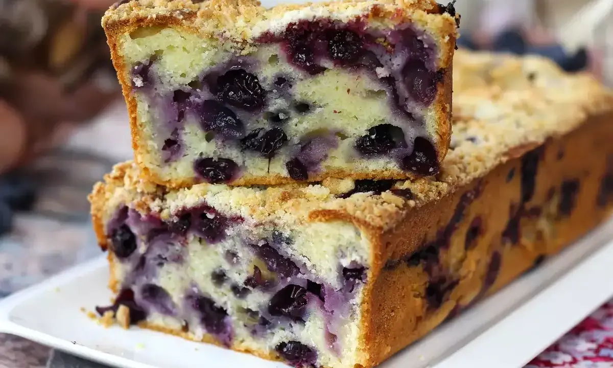 Saftiger Heidelbeerkuchen mit Streuseln, ein Stück gestapelt auf dem ganzen Kuchen.