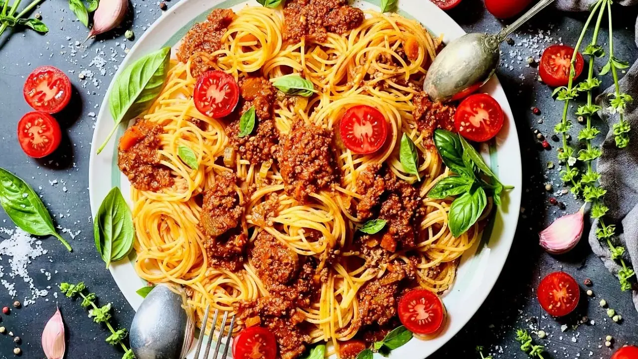Spaghetti Bolognese mit Hackfleisch, garniert mit frischen Tomaten und Basilikum. Ein Klassiker, bei dem das bolognese welches Fleisch zur Geltung kommt.
