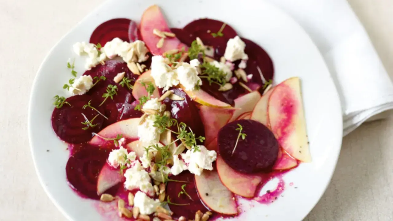 Ein bunter Rote Bete Salat mit Apfelscheiben, zerbröckeltem Käse, Sonnenblumenkernen und Kresse.