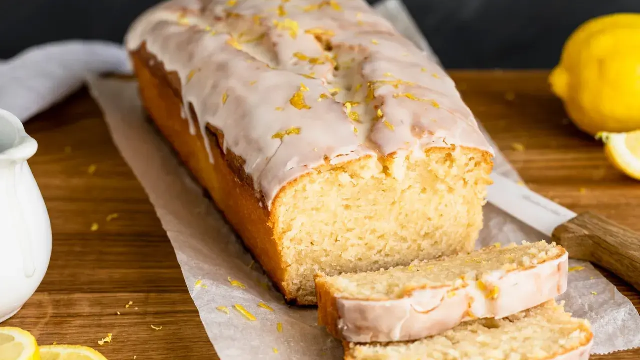 Saftiger veganer Zitronenkuchen mit Zuckerguss und Zitronenschale bestreut. Ein köstlicher Genuss!