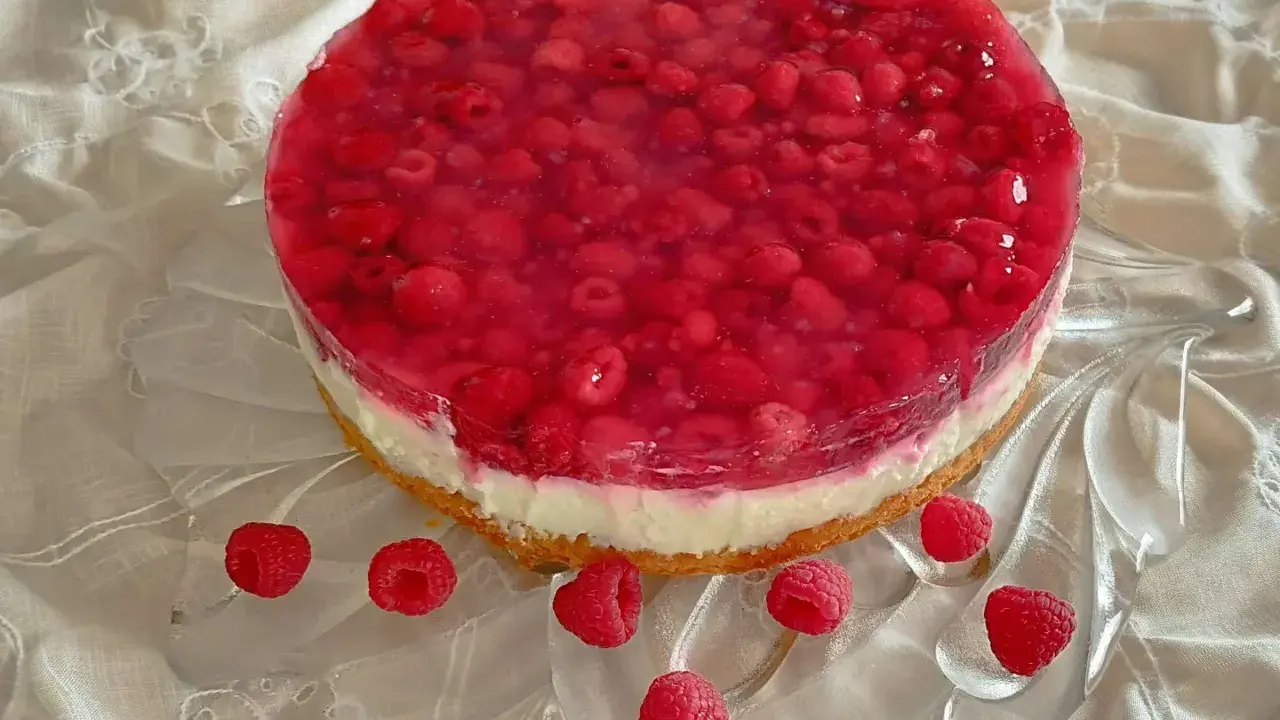 Himbeer Joghurt Torte mit frischen Himbeeren und Tortenguss auf einem cremigen Boden, verziert mit einzelnen Himbeeren.