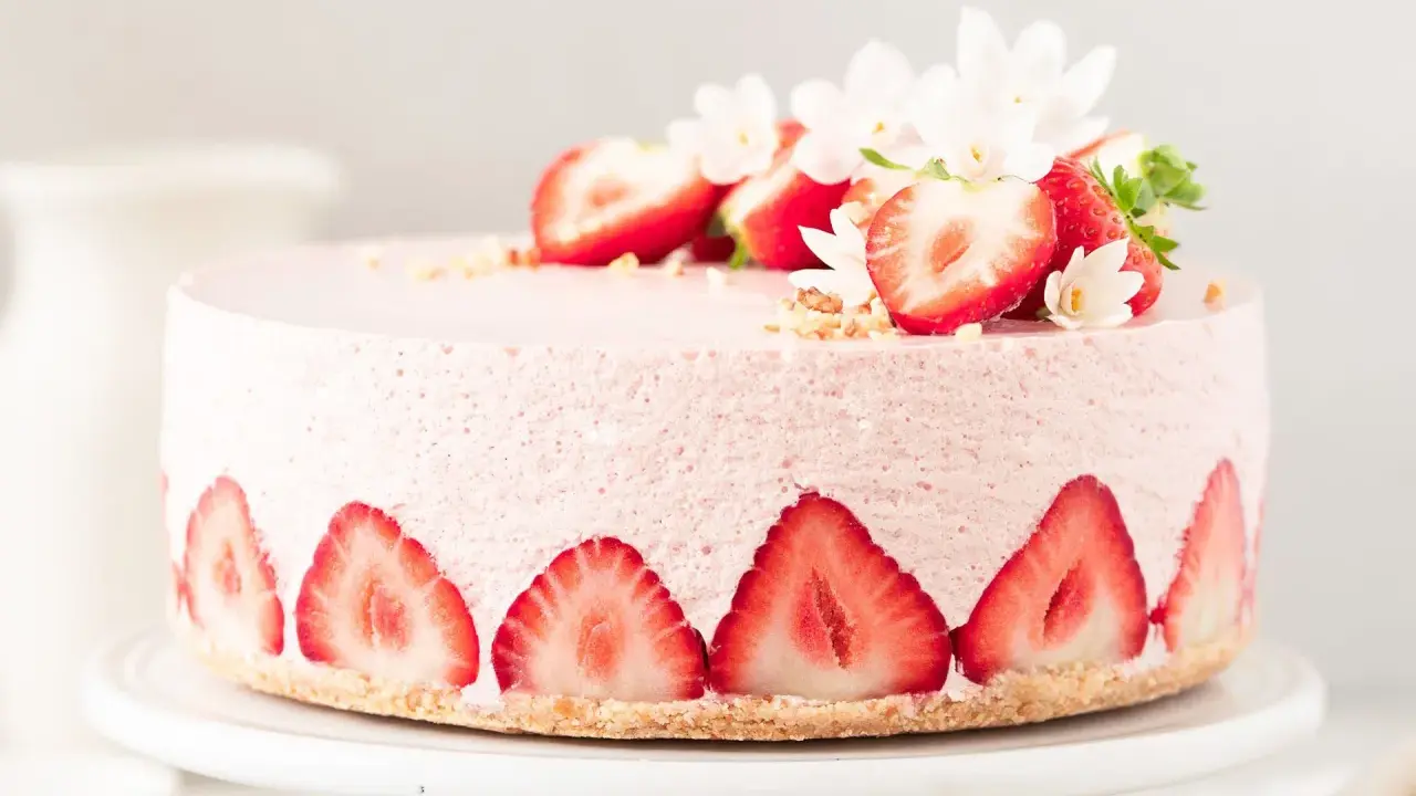 Ein zarter Erdbeer Cheesecake, verziert mit frischen Erdbeerscheiben und Blüten. Dieses Erdbeer Cheesecake Rezept sieht köstlich aus!