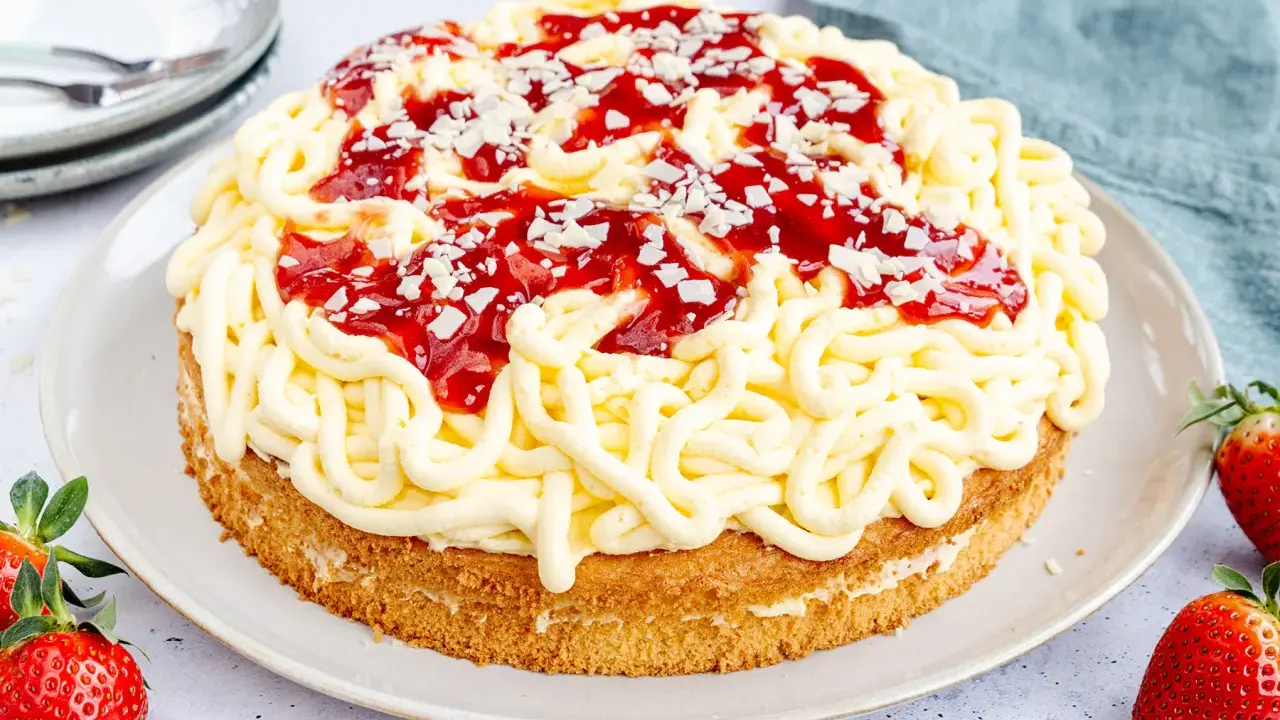 Eine Spaghettieis Torte mit Erdbeersoße und weißen Schokostückchen, die an Spaghetti erinnert.