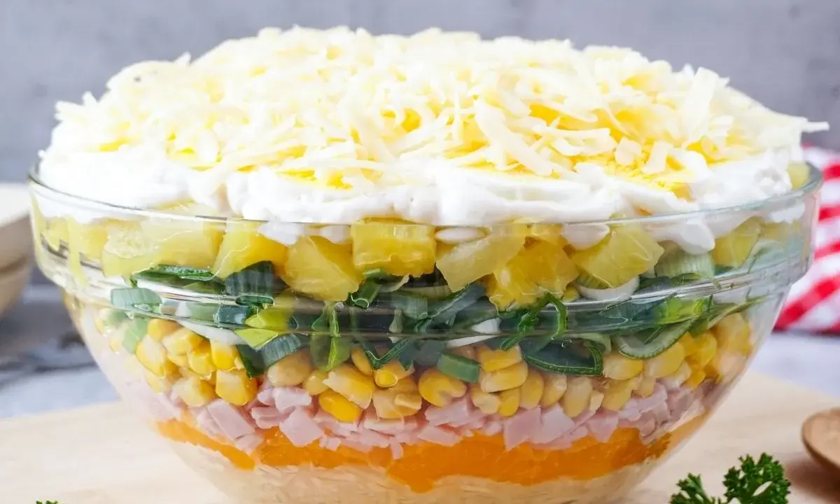 Schichtsalat-Rezept: Bunter Salat mit Ananas, Mais, Schinken, Lauch und Käse in einer Glasschüssel.