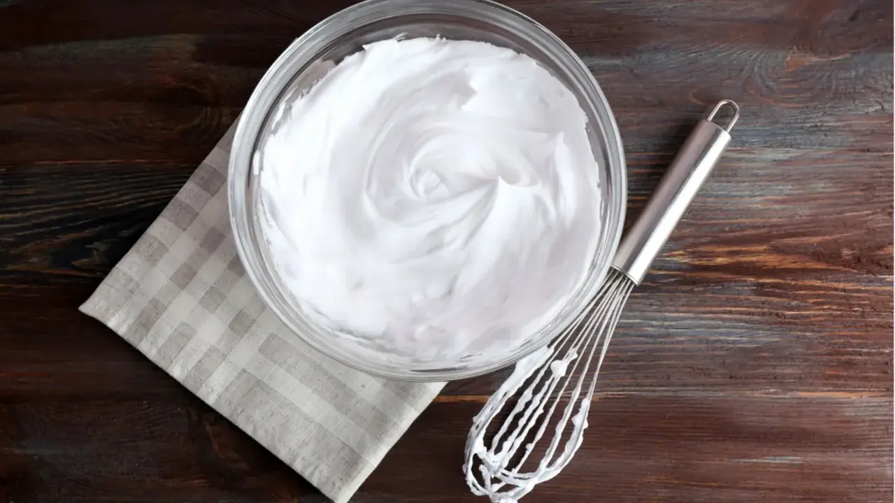 Schneebesen neben Schüssel mit steif geschlagenem Eiweiß. Eine tolle Alternative, wenn man fragt, was kann man statt Sahne nehmen.
