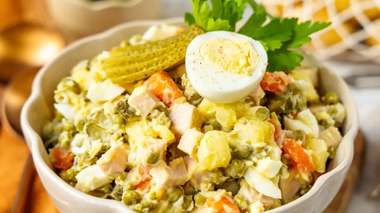 Ein köstlicher Olivier Salat, garniert mit Ei und Gurke, bereit zum Genießen.