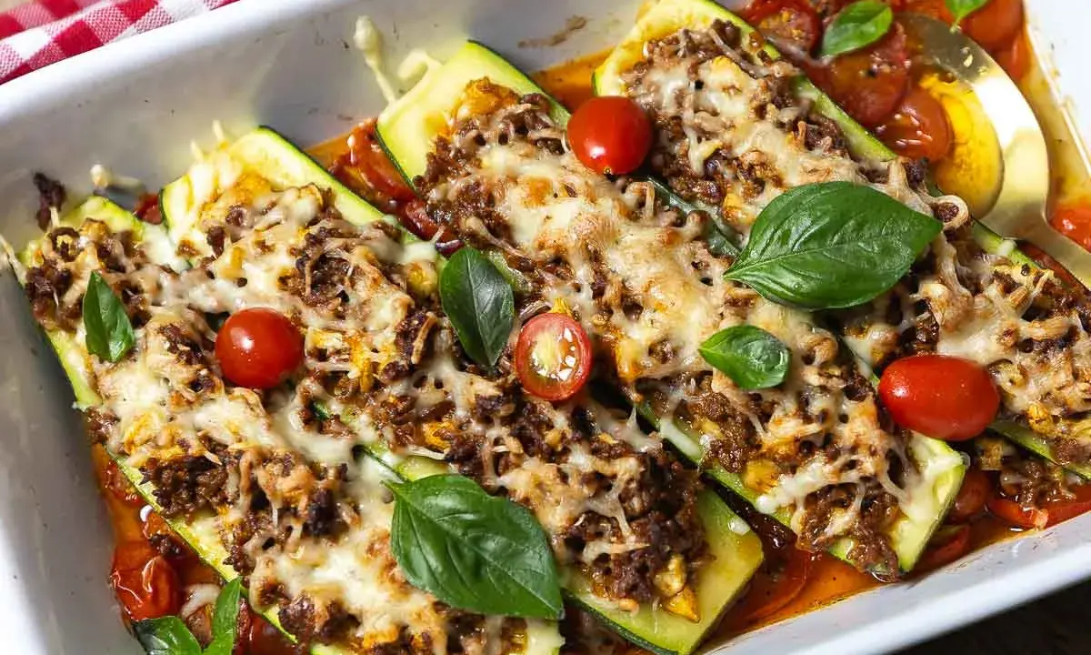 Gefüllte Zucchini mit Hackfleisch, überbacken mit Käse und garniert mit Tomaten und Basilikum. Ein köstliches Gericht!