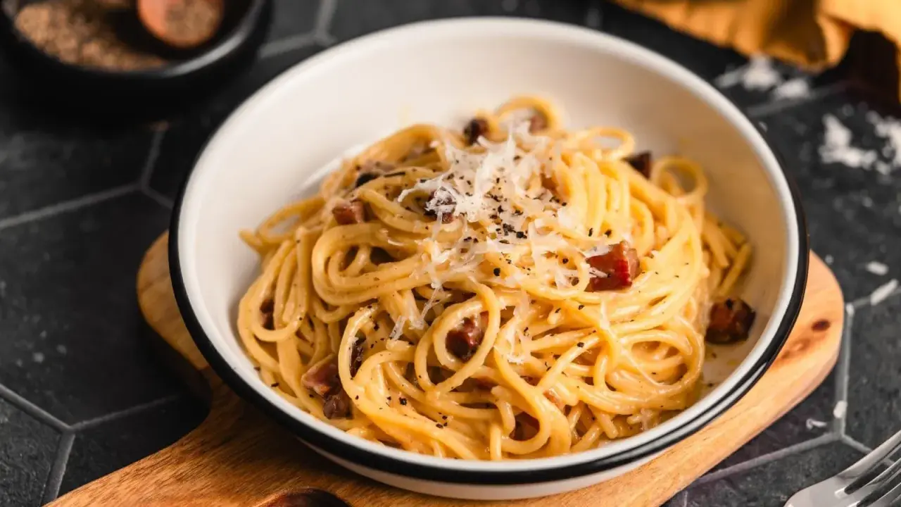 Ein Teller Spaghetti Carbonara, garniert mit Parmesan und schwarzem Pfeffer. Perfekt für authentische Carbonara Rezepte.