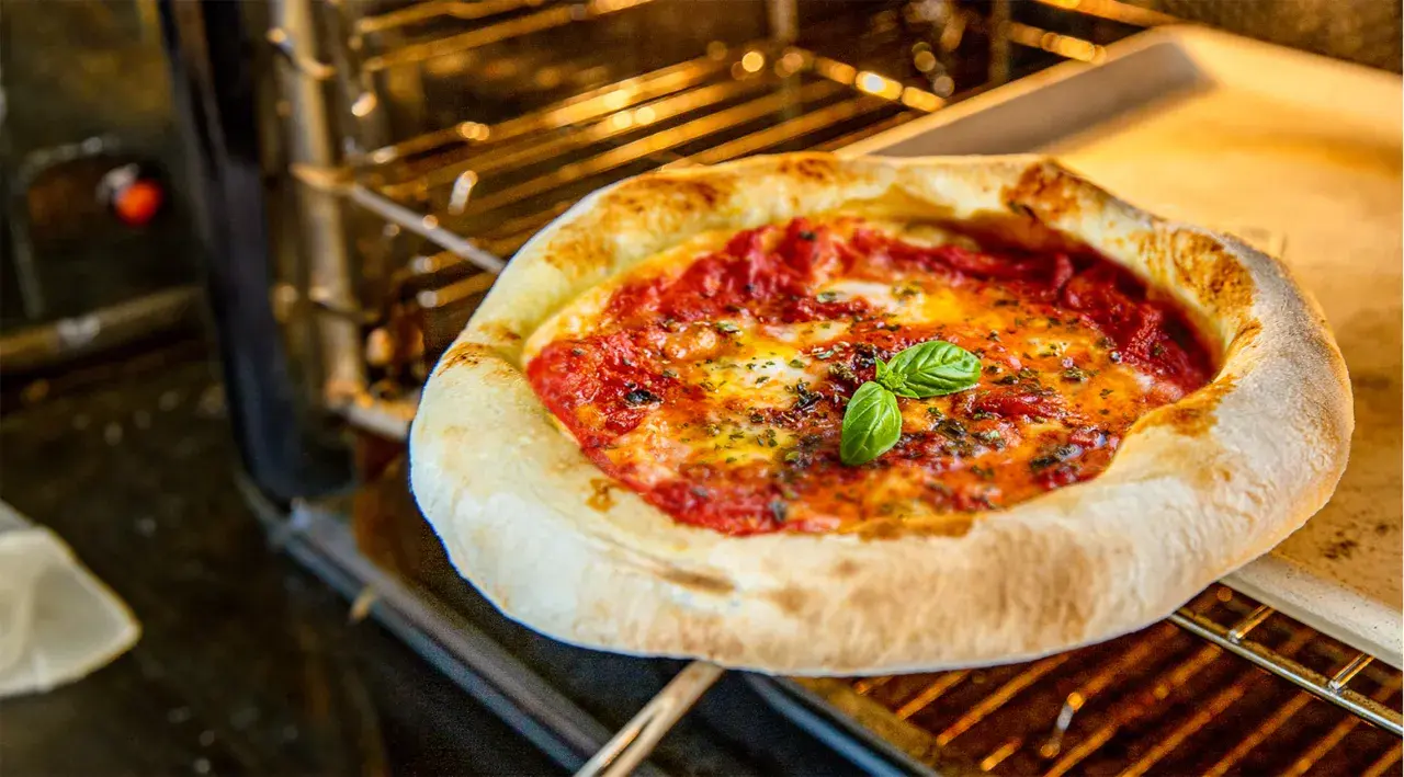 Eine köstliche Pizza mit geschmolzenem Käse und frischem Basilikum wird im Backofen gebacken.