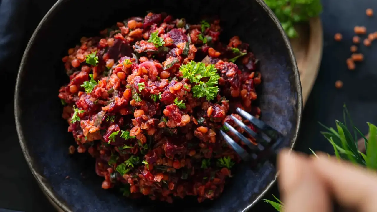 Ein köstlicher rote Linsen Salat mit Roter Bete und frischer Petersilie, serviert in einer dunklen Schüssel.