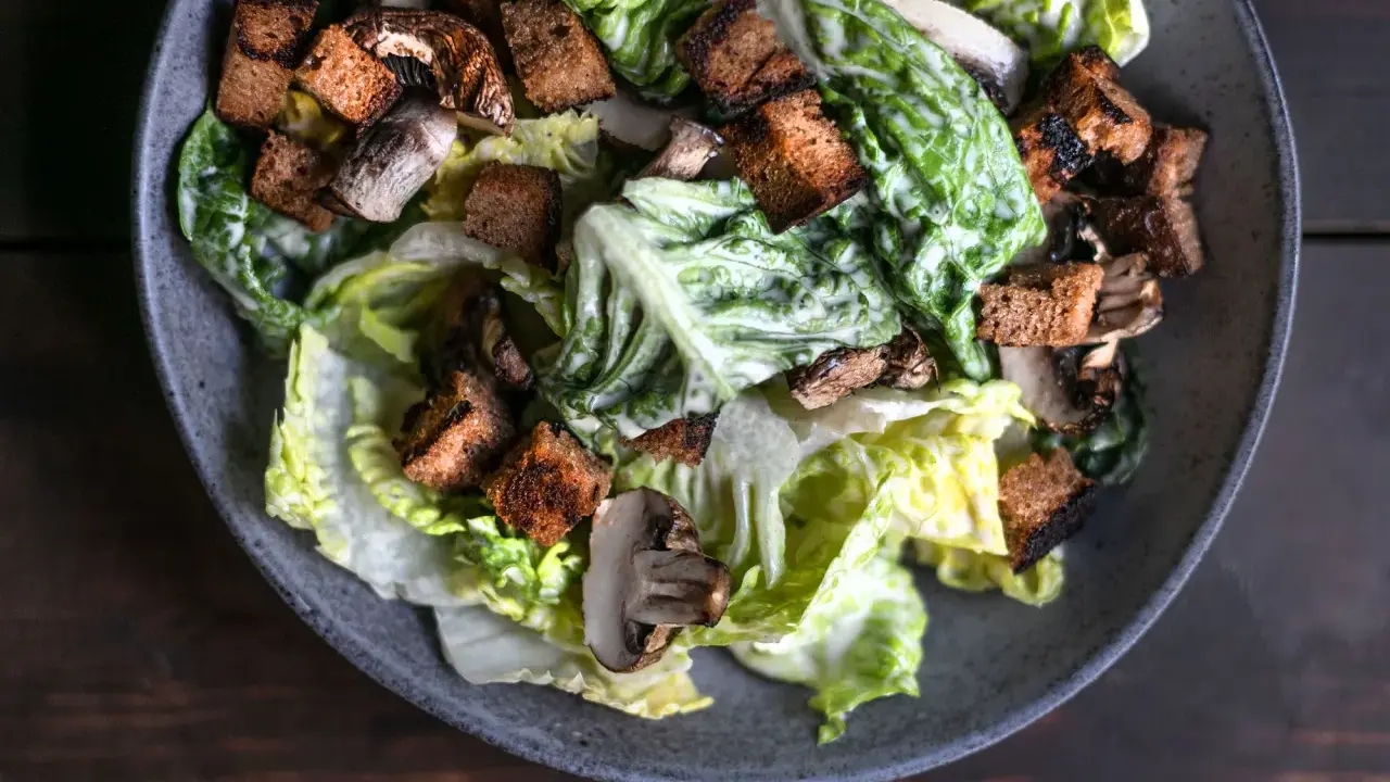 Herzhafter Caesar Salad mit knackigem Römersalat, gerösteten Croutons und Pilzen, übergossen mit cremiger Sauce.