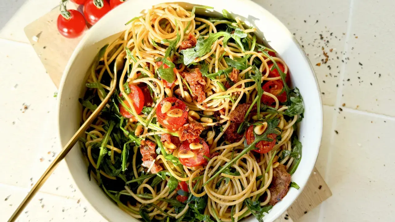 Mediterraner Salat mit getrockneten Tomaten und Rucola, garniert mit Pinienkernen. Ein köstliches Gericht, das nach Sommer schmeckt.