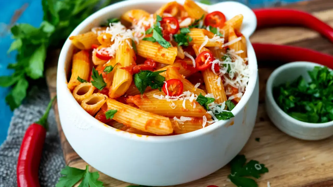 Eine Schüssel Penne all'Arrabbiata, garniert mit frischer Petersilie und Chilischeiben.