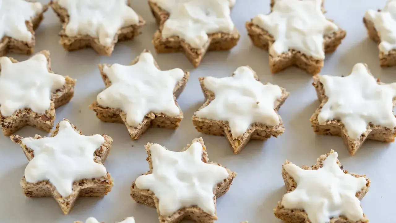 Klassisches zimtsterne rezept: Sterne aus Nüssen, mit weißer Glasur überzogen, bereit zum Genießen.