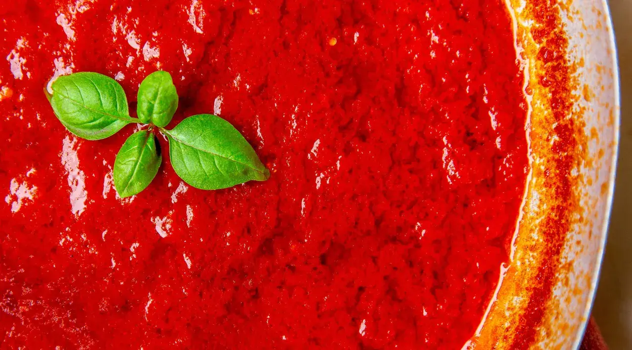 Frische, leuchtend rote italienische Tomatensauce mit Basilikumblättern, bereit für Pasta.