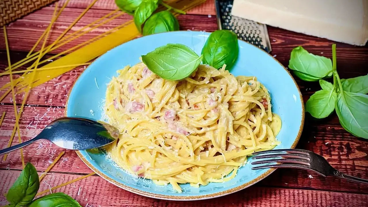 Herzhafte Spaghetti Carbonara mit Speck, garniert mit frischem Basilikum und Parmesan. Ein Klassiker, der immer schmeckt.