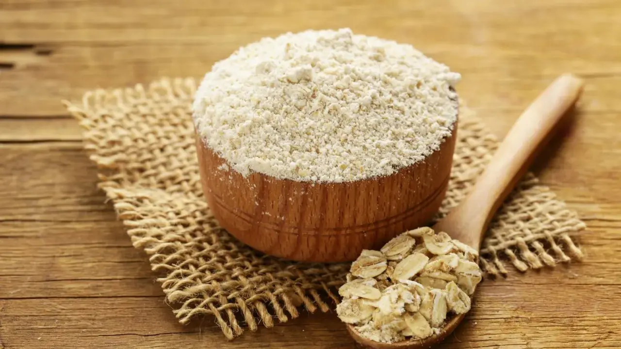 Holzschale mit feinem Hafermehl und Löffel voller Haferflocken. Perfekt zum Backen mit Hafermehl.