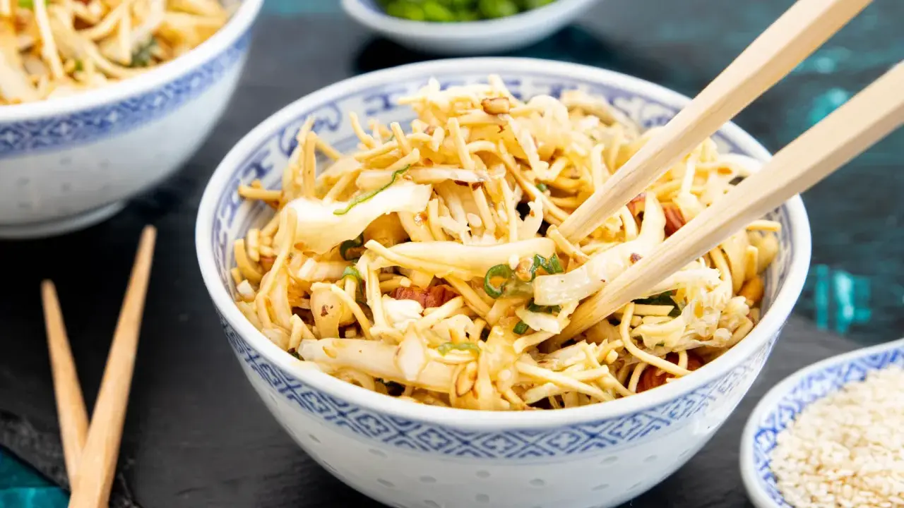 Ein Schüsselchen "friss dich dumm Salat" mit Nudeln, Gemüse und Erdnüssen, bereit zum Genießen mit Stäbchen.