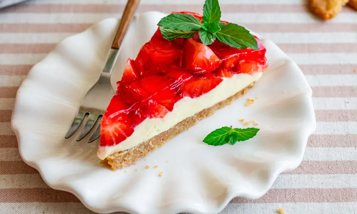 Ein Stück Erdbeerkuchen mit Frischkäsefüllung und glasierten Erdbeeren, garniert mit Minze. Perfekt für einen 5 min kuchen ohne backen.