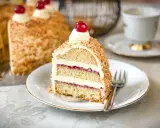Ein Stück Frankfurter Kranz mit Buttercreme und Kirschen, umhüllt von gehackten Nüssen. Ein Genuss für jeden Kaffeetisch.