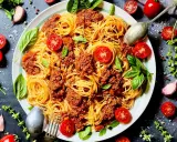 Spaghetti Bolognese mit Hackfleisch, garniert mit frischen Tomaten und Basilikum. Ein Klassiker, bei dem das bolognese welches Fleisch zur Geltung kommt.