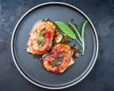 Zwei in Prosciutto eingewickelte Fleischstücke mit Salbei, glasiert und auf einem Teller serviert. Ein köstliches Beispiel für italienische Gerichte.