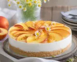 Ein köstlicher Kuchen ohne Backen, belegt mit frischen Pfirsichscheiben und kleinen Gänseblümchen.