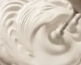 Schlagende Sahne wird mit einem Handmixer zu steifen Spitzen aufgeschlagen, bereit für köstliche Desserts.