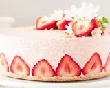 Ein zarter Erdbeer Cheesecake, verziert mit frischen Erdbeerscheiben und Blüten. Dieses Erdbeer Cheesecake Rezept sieht köstlich aus!