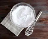 Schneebesen neben Schüssel mit steif geschlagenem Eiweiß. Eine tolle Alternative, wenn man fragt, was kann man statt Sahne nehmen.