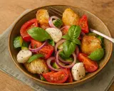 Ein köstliches Panzanella Rezept mit frischen Tomaten, Gurken, Mozzarella, roten Zwiebeln und knusprigen Brotwürfeln, garniert mit Basilikum.