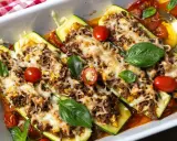 Gefüllte Zucchini mit Hackfleisch, überbacken mit Käse und garniert mit Tomaten und Basilikum. Ein köstliches Gericht!