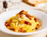 Spaghetti Carbonara mit knuspriger Pancetta, cremigem Ei und Käse bestreut. Ein Klassiker der italienischen Küche.