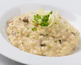Cremiger Pilz-Risotto-Reis, garniert mit Parmesan und Schnittlauch, serviert in einer weißen Schüssel.