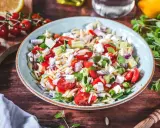 Frischer Kritharaki Salat mit Tomaten, Gurken, Feta und roten Zwiebeln, garniert mit Kräutern. Ein leichter Genuss!