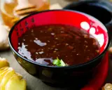 Schwarze Schüssel mit glänzender Teriyaki-Sauce, umgeben von Ingwer, Chili und Honig. Perfekt für dein Teriyaki Sauce Rezept!