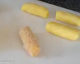 Vier Kartoffelstäbchen liegen auf einem Schneidebrett. Eines ist bereits paniert, die anderen drei warten darauf, dass sie **kroketten selber machen** können.