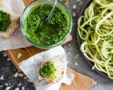 Frisches Basilikumpesto rezept in einem Glas, daneben Brot mit Pesto und eine Portion Spaghetti. Perfekt für ein schnelles Mittagessen.