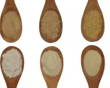 Sechs Holzlöffel mit verschiedenen Mehlsorten: feines, grobes und griffiges Mehl sowie Grieß.