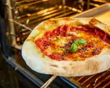 Eine köstliche Pizza mit geschmolzenem Käse und frischem Basilikum wird im Backofen gebacken.