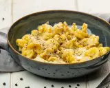 Eine Schüssel mit italienischen Nudeln, bestreut mit Parmesan und schwarzem Pfeffer, serviert auf einem rustikalen Tisch.