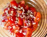Frischer Tomatensalat mit roten Zwiebeln und Kräutern, bereit für Feta.