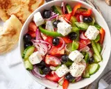 Frischer griechischer Salat mit Tomaten, Gurken, roten Zwiebeln, Oliven und Feta-Käse, serviert mit Fladenbrot.