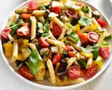 Bunter Nudelsalat ohne Mayo mit Penne, gegrilltem Gemüse wie Zucchini, Aubergine, Paprika und Kirschtomaten, garniert mit Basilikum und Parmesan.