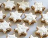 Klassisches zimtsterne rezept: Sterne aus Nüssen, mit weißer Glasur überzogen, bereit zum Genießen.