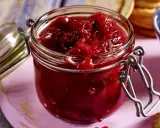 Ein Glas mit leuchtend rotem Zwetschgen-Chutney, bereit, zu Käse oder Gebäck serviert zu werden.