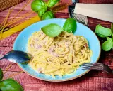 Herzhafte Spaghetti Carbonara mit Speck, garniert mit frischem Basilikum und Parmesan. Ein Klassiker, der immer schmeckt.