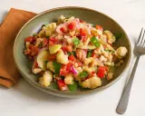 Bunter Panzanella Salat mit Tomaten, Gurken, roten Zwiebeln und knusprigem Brot in einer grünen Schüssel.