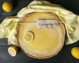 Ein frisch gebackener Joghurt Zitronen Kuchen mit einer Zitronenscheibe und dem Schriftzug "Homemade" auf einem gelben Tuch.